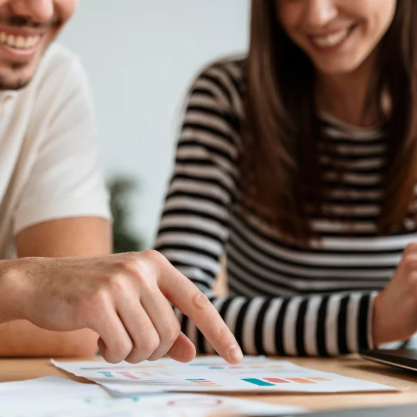 A man and woman are focused on a laptop screen, discussing strategies to get out of debt.