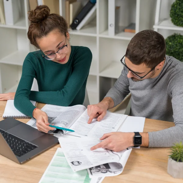 A man and woman collaborate on paperwork at a desk, discussing options for obtaining a personal loan in Canada.