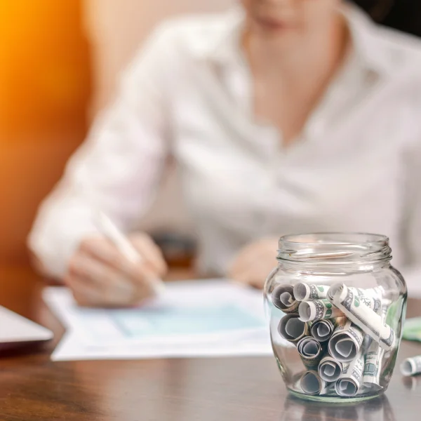 A woman sitting at a desk with a jar of coins, contemplating options for a personal loan in Canada.